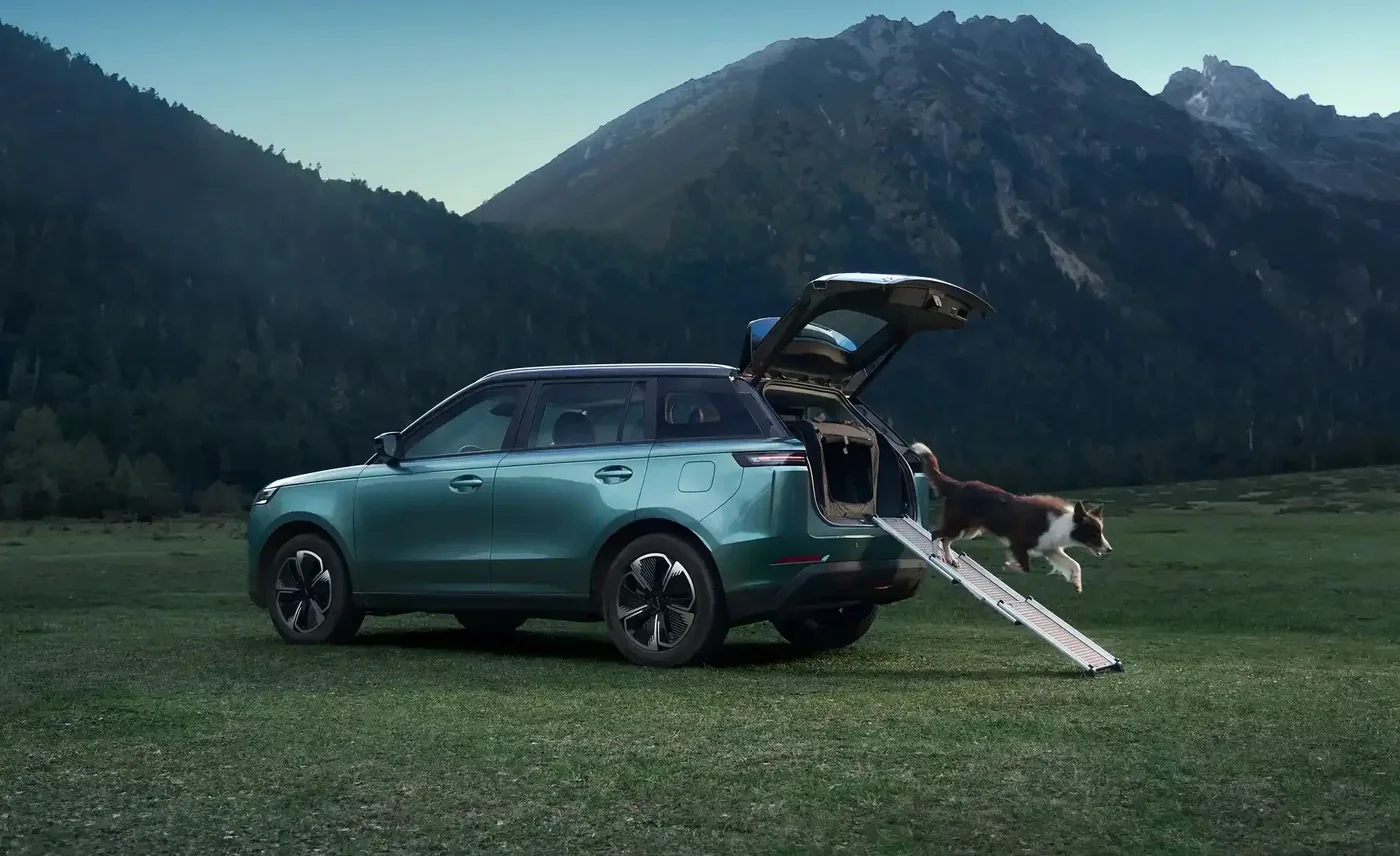 Jaecoo J5 EV with the powered tailgate open in a meadow