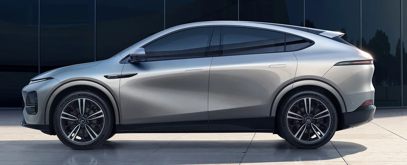 Silver XPENG G6 side profile in front of a glass building
